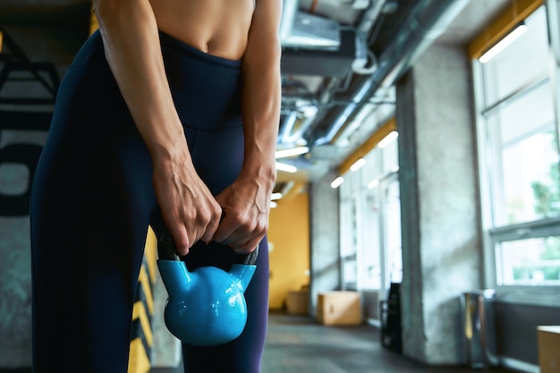 Weight training cropped shot of a strong athletic woman exercising with dumbbell at industrial gym