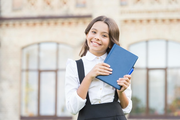 Welcome back to school Happy little girl go from school library Cute primary school child smile with book in hands Prep for school September 1 Knowledge day Early education