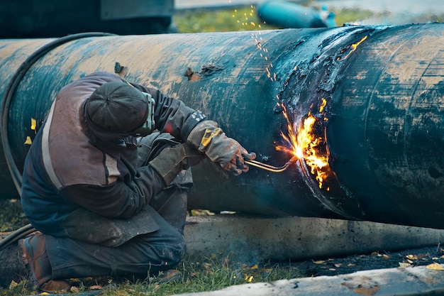 The welder cuts large metal pipes with ocetylene welding