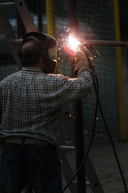 Welder is welding metal part in playground Hand welder in protective glove Welding sparks