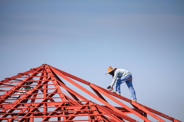 welder workers installing steel frame structure of the house roof