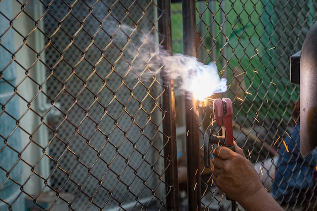 The welders are welding doors to protect the property at dark background