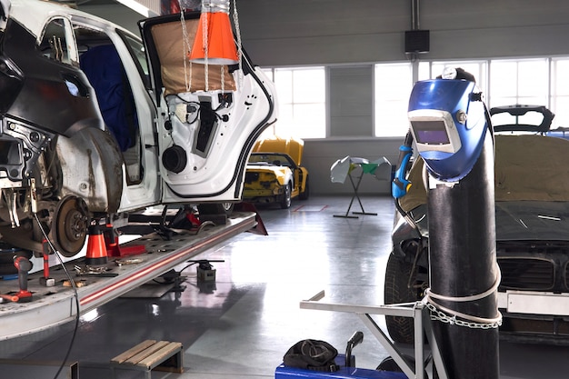 Welding equipment in a car repair station, helmet hanging on a gas tank, no people