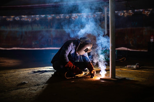 Welding male worker metal is part in machinery tank plate bottom construction petroleum oil and gas storage tank inside confined spaces.