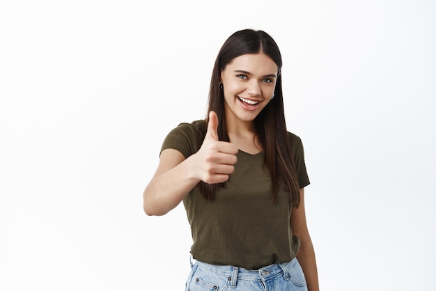 Well done great work Smiling confident woman encourage you stretch out hand with thumb up approve or praise good choice give positive feedback like product white background