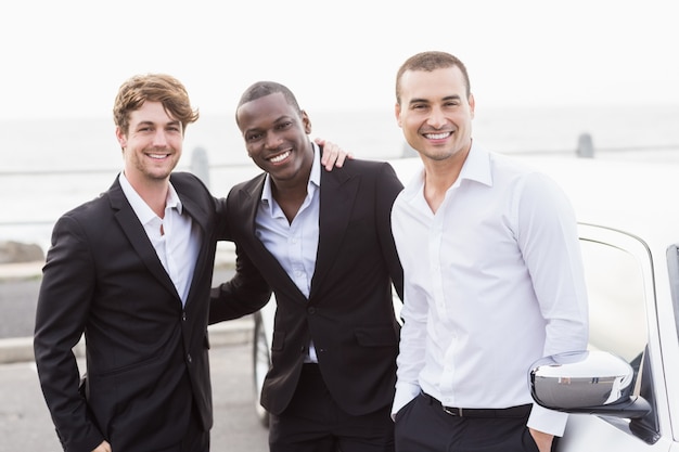 Well dressed men posing next to a limousine