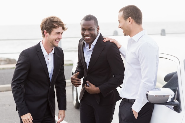 Well dressed people posing next to a limousine