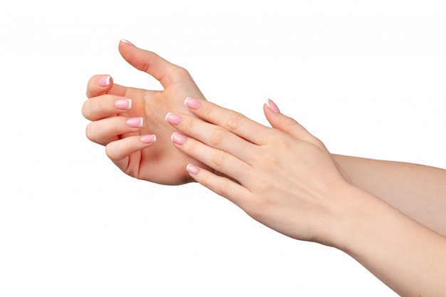 Well-groomed female hands with manicure on white wall