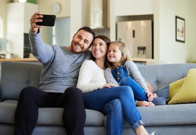 Well have these memories forever Shot of a young family taking a selfie on the couch at home