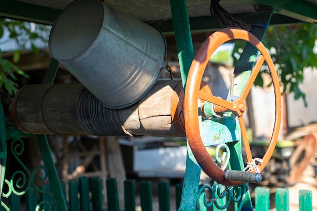 A well with a bucket in a European village Sunny day Metal bucket for a water well Detail of a well