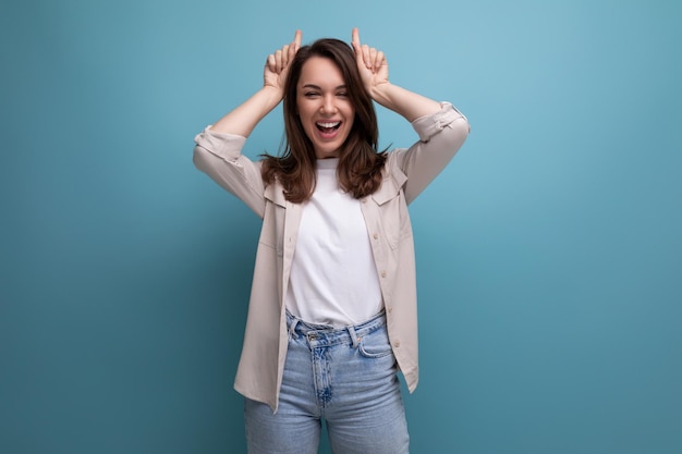 Wellgroomed brunette young woman in a stylish image posing on a blue background with copy space