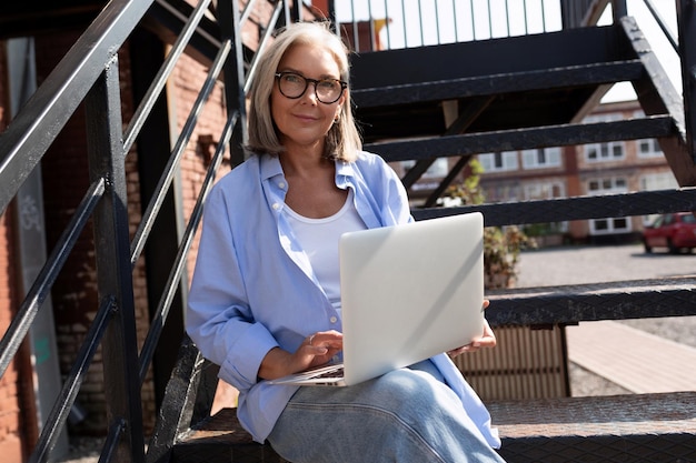 Wellgroomed middleaged woman with a bob haircut works freely using a laptop on the street