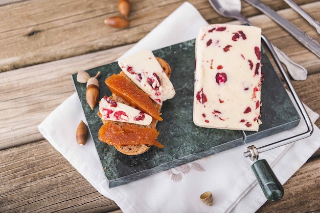 Wensleydale cheese with cranberries red wine honey nuts raisins on marble cutting board Black concrete background Selective focus