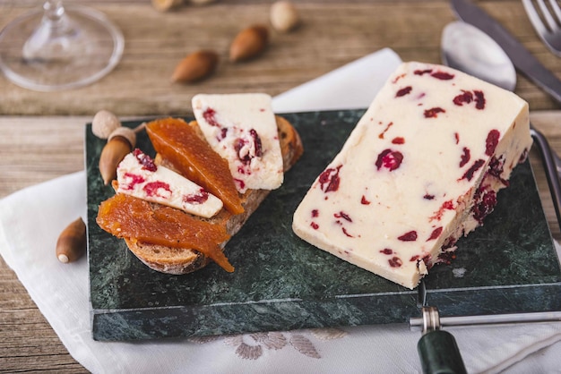 Wensleydale cheese with cranberries red wine honey nuts raisins on wooden cutting board Black concrete background Selective focus