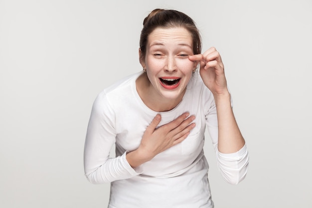 Werry funny joke. Emotional young freackles woman toothy smiling and cry. Studio shot, isolated on gray background