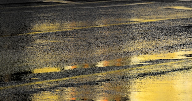 Wet asphalt road with Golden reflections of the night city lights, soft focus