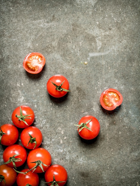 Wet red tomatoes on the stone table.