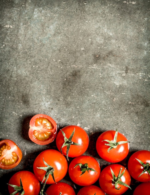 Wet red tomatoes on the stone table.