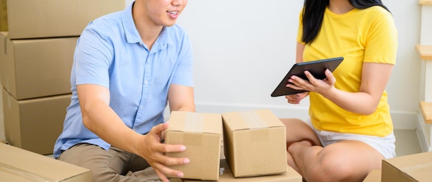 WFH: Thai entrepreneur couple are packing the box. Selling online and home delivery. Teamwork for Startup SME business and work from home concept. Social Distancing and Physical Distancing.