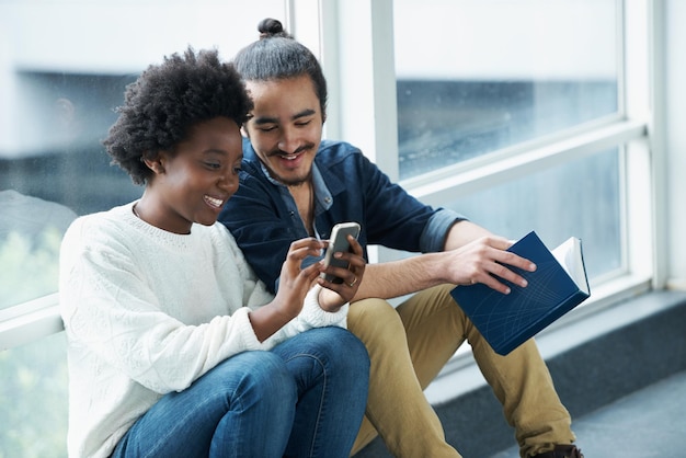 What did she say A college couple sitting closely together looking at a message on one of their phones