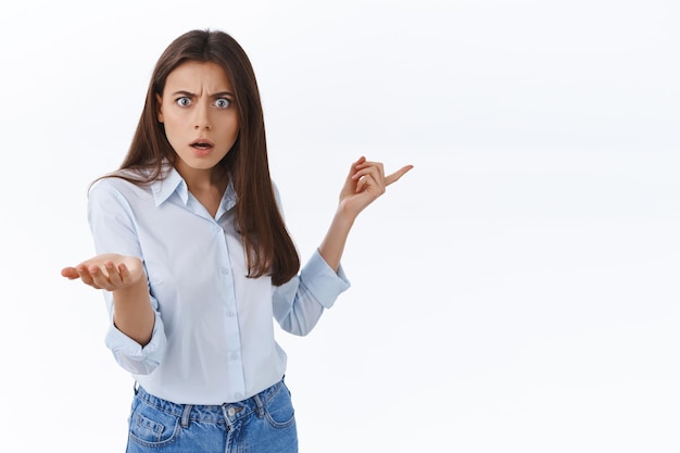 What the hell is that. Confused and frustrated annoyed young adult woman pointing right and demand answer on question as scolding team member for ruined project