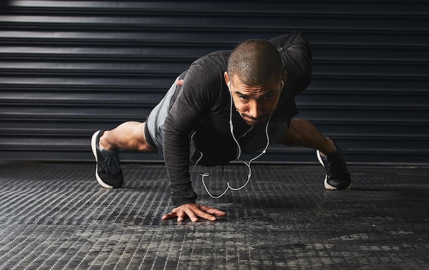 What hurts now will one day be your warm up Shot of an athletic young man doing pushups in the gym