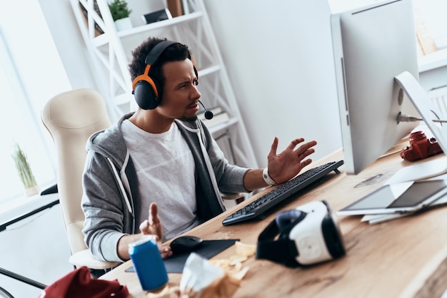 What is happening? Frustrated young man in casual clothing using computer while spending time at home