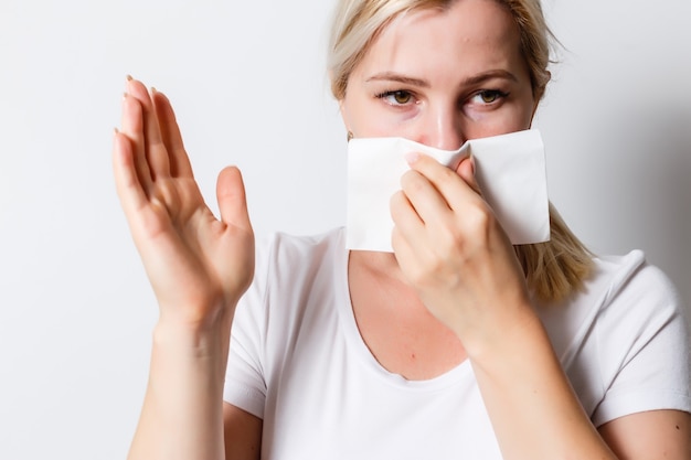 What a smell. Close up of young unhappy student girl with long hair in casual t-shirt squeezing nose with fingers, looking in camera with disgust expression, feeling bad about bad smell on street