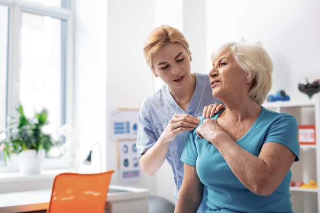 What do you feel. Professional female masseuse touching her patients shoulder while doing the massage