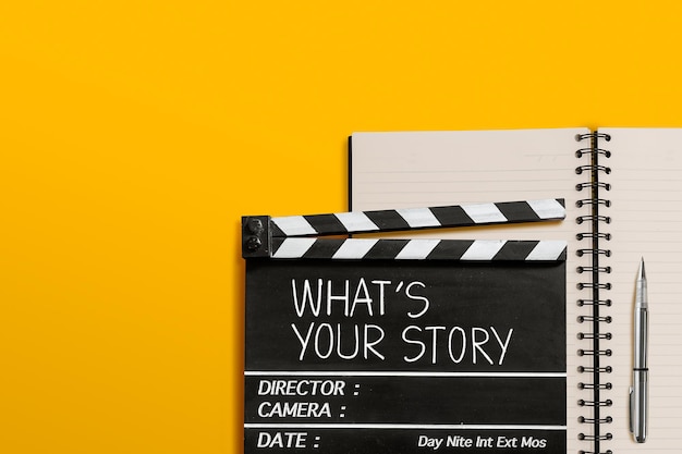 Whats your storyText title on movie clapperboard and notebook on yellow background