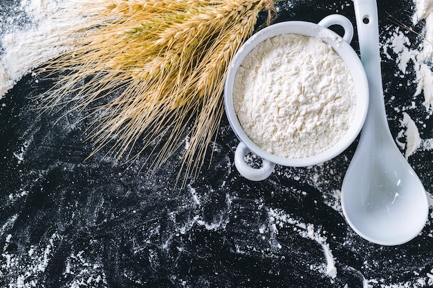 Wheat ears and flour on black background