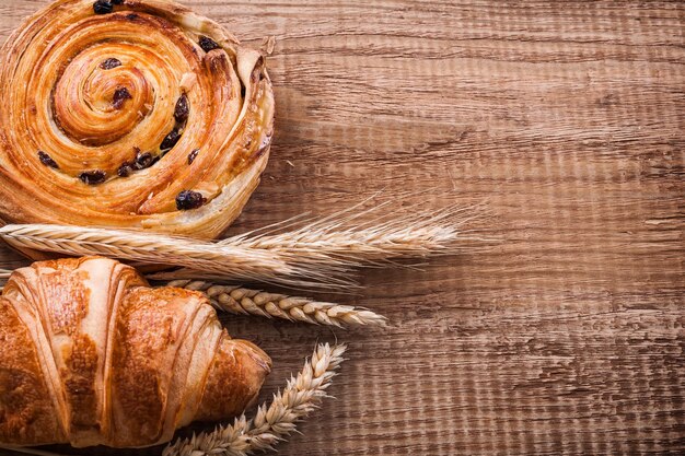 Wheat ears raisin bun croissant on oak wooden board food and drink concept