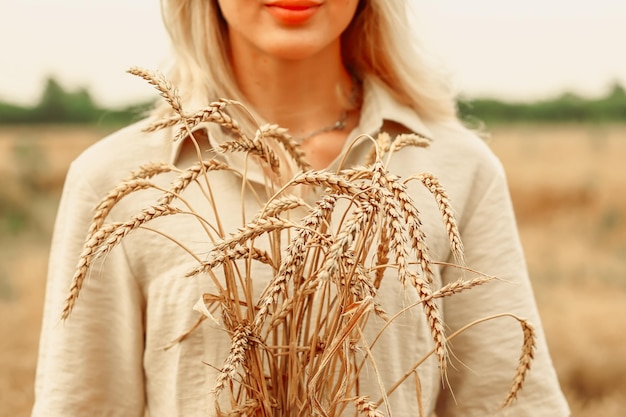 Wheat field The concept of the global food crisis Woman holding ears of wheat in her hands