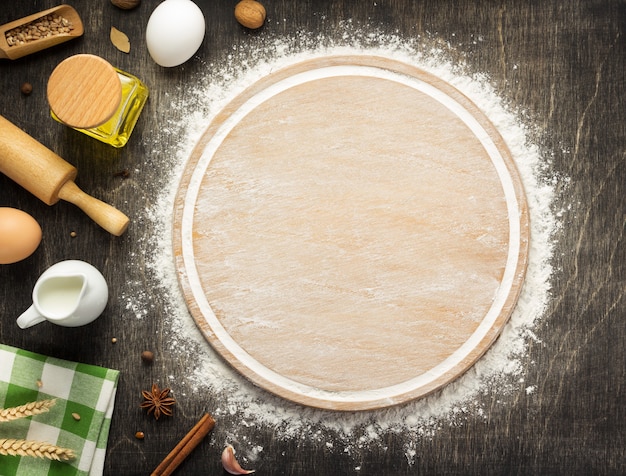 Photo wheat flour and cutting board on wooden background, top view