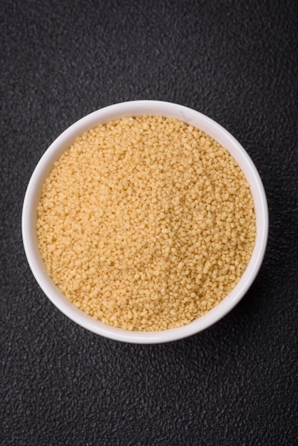 Wheat porridge couscous grains on a dark concrete background