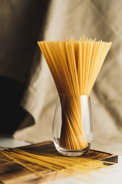 Wheat spaghetti pasta in glass on a wooden board