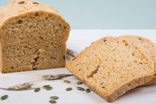 Wheat yeast rustic bread with pumpkin seeds on white wooden board surface Studio Photo