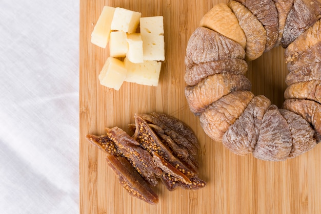 Wheel of dried figs with a dry fig cut into slices next to pieces of pecorino cheese