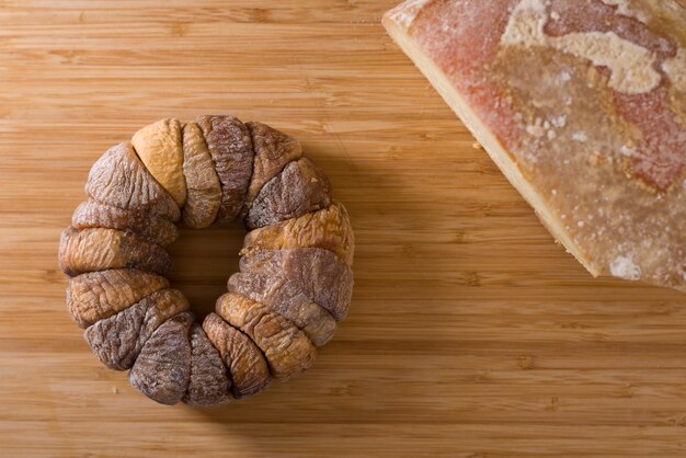 Wheel of dried figs with a pecorino on top of wooden board on a white tablecloth