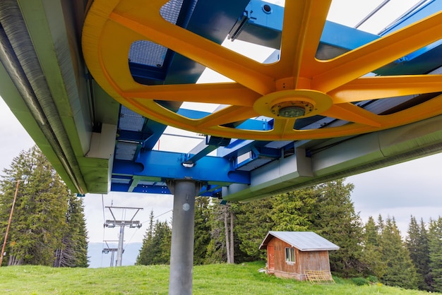 Wheel in a mechanism on a lift in a mountain forest against a cloudy sky