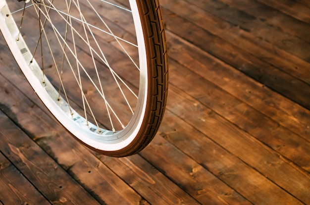 Wheel of a stylish bicycle with a white rim and a brown rubber tire on a stylish wooden