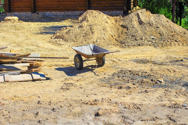 Wheelbarrow on the   building yard among the sand and boards