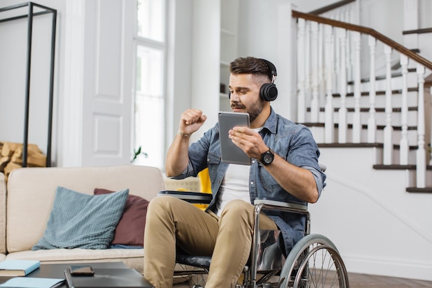 Wheelchair user with headphones listening music on tablet