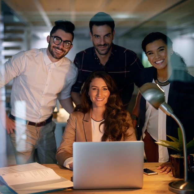 When you love your job you dont watch the clock Portrait of a group of businesspeople using a laptop while working overtime in the office