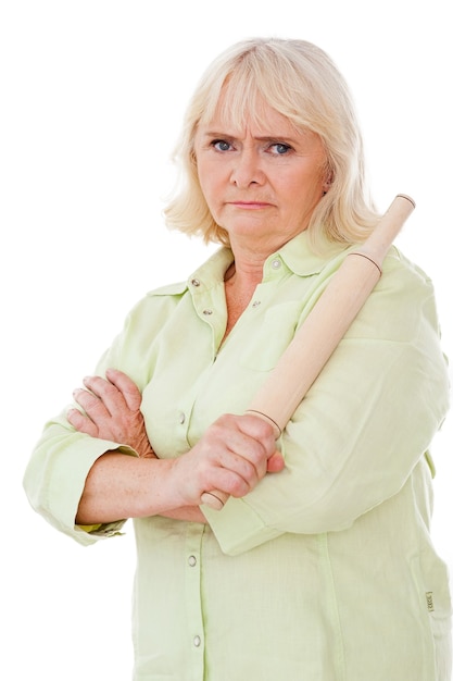 Where have you been?  Angry senior woman holding rolling pin and looking at camera while standing isolated on white background