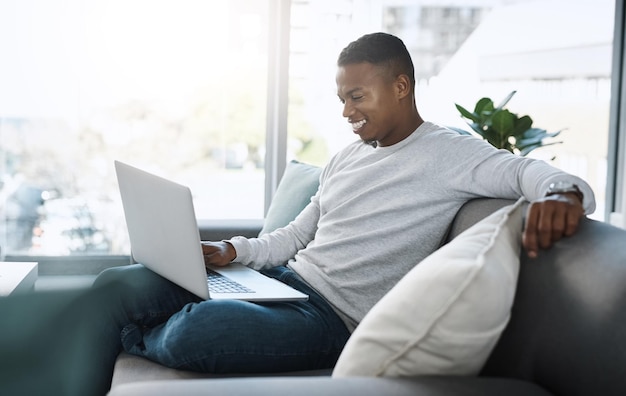 Where do I sign up for this content Shot of a handsome young man using his laptop while sitting on a sofa at home