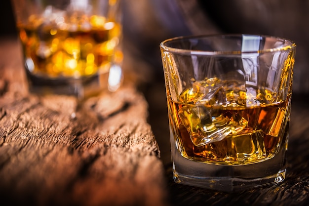 Whiskey drink. Whiskey drinks on rustic oak wood with ice cubes.