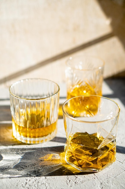 Whiskey in glasses on table in bright sunlight yellow drink