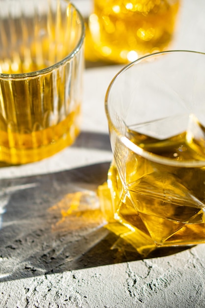 Whiskey in glasses on table in bright sunlight yellow drink