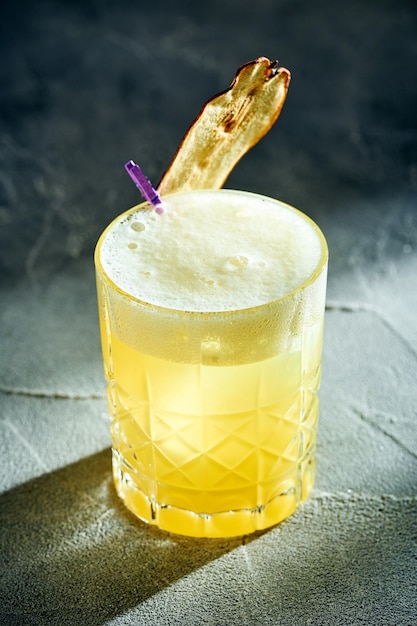 Whiskey sour cocktail with egg yolk on a concrete background Yellow alcoholic cocktail with hard light